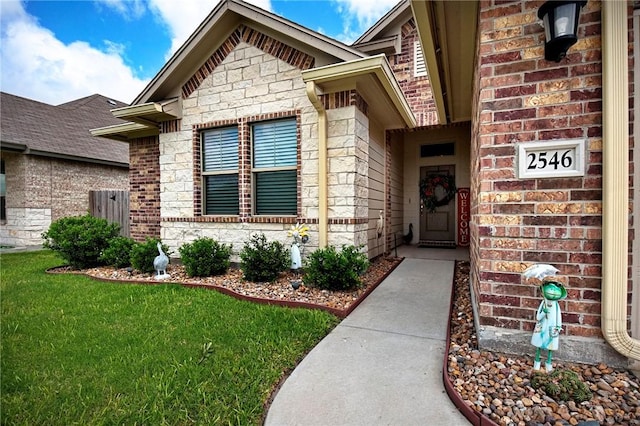 property entrance with a yard, brick siding, and stone siding