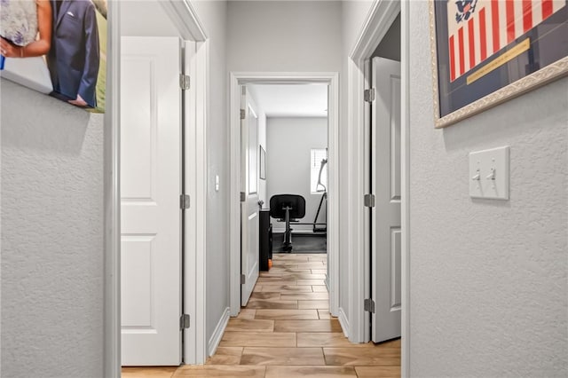 hallway featuring wood tiled floor and a textured wall