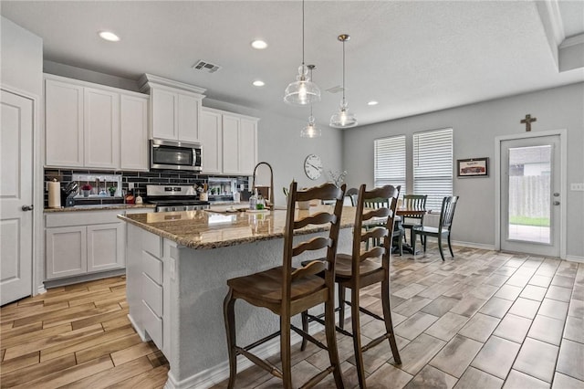 kitchen with a sink, stainless steel appliances, recessed lighting, backsplash, and visible vents