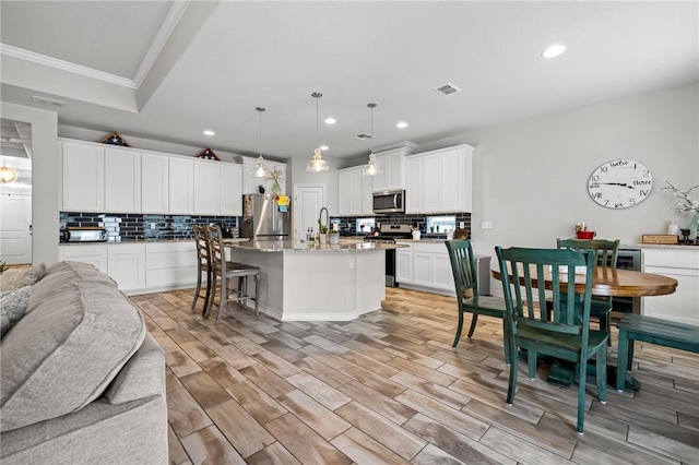 kitchen featuring visible vents, appliances with stainless steel finishes, open floor plan, ornamental molding, and recessed lighting