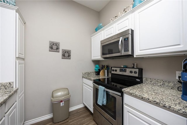 kitchen featuring light stone counters, dark wood-style flooring, baseboards, white cabinets, and appliances with stainless steel finishes