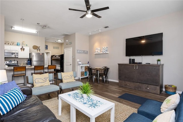 living area featuring visible vents, wood finished floors, a ceiling fan, and baseboards