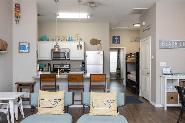 kitchen with a peninsula, dark wood-style flooring, visible vents, white cabinetry, and appliances with stainless steel finishes