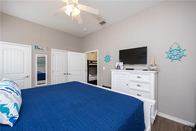 bedroom featuring a ceiling fan, visible vents, baseboards, dark wood-style floors, and two closets