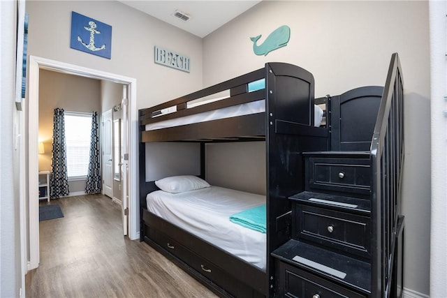 bedroom featuring wood finished floors, visible vents, and baseboards