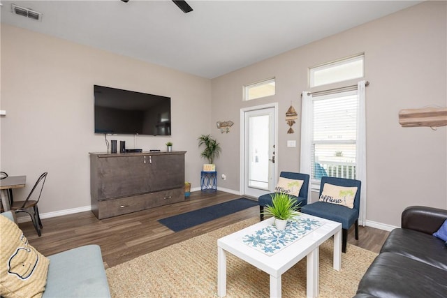 living room with ceiling fan, wood finished floors, visible vents, and baseboards