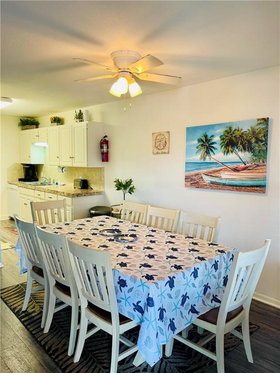 dining space with ceiling fan, dark wood-type flooring, and sink