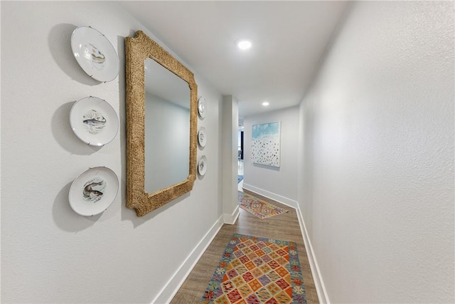 hall featuring baseboards, wood finished floors, and recessed lighting