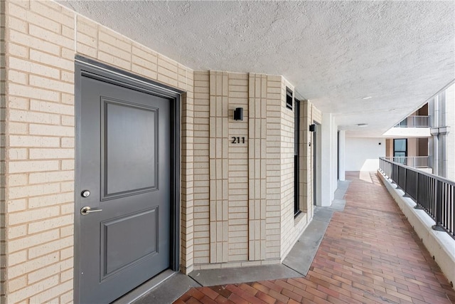 property entrance with brick siding and a balcony