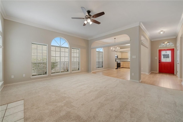 unfurnished living room with ceiling fan with notable chandelier, crown molding, and light carpet