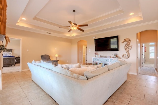 living room with ceiling fan, a raised ceiling, and ornamental molding