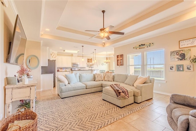 tiled living room with ceiling fan, a raised ceiling, and ornamental molding