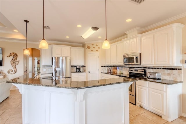 kitchen featuring white cabinetry, dark stone countertops, pendant lighting, a center island with sink, and appliances with stainless steel finishes