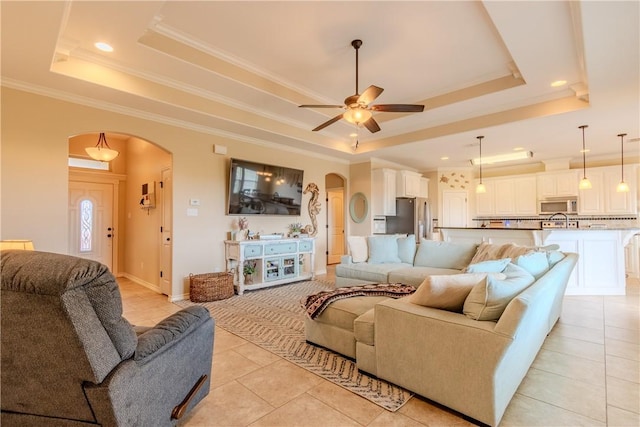 tiled living room with ceiling fan, a raised ceiling, and ornamental molding