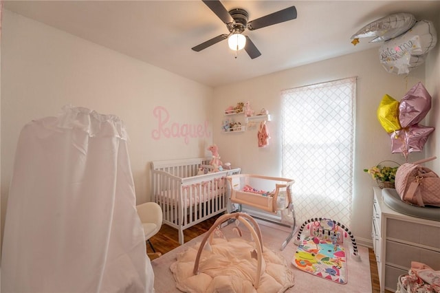 bedroom featuring ceiling fan, wood-type flooring, and a crib