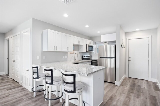 1107 E 11th St Unit H58, Port Aransas, TX 78373 - kitchen featuring white cabinets, a peninsula, a sink, light stone countertops, and appliances with stainless steel finishes