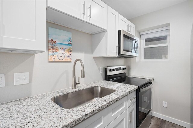 1107 E 11th St Unit H58, Port Aransas, TX 78373 - kitchen with stainless steel appliances, white cabinetry, a sink, light stone countertops, and dark wood-style flooring