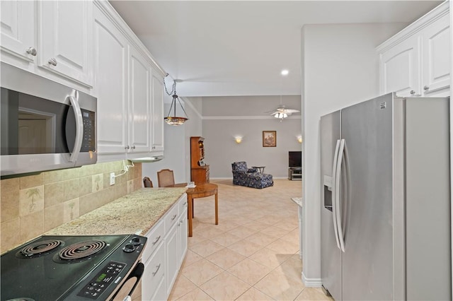 kitchen featuring white cabinets, light stone countertops, stainless steel appliances, and backsplash