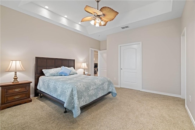 bedroom featuring baseboards, visible vents, a tray ceiling, and light colored carpet