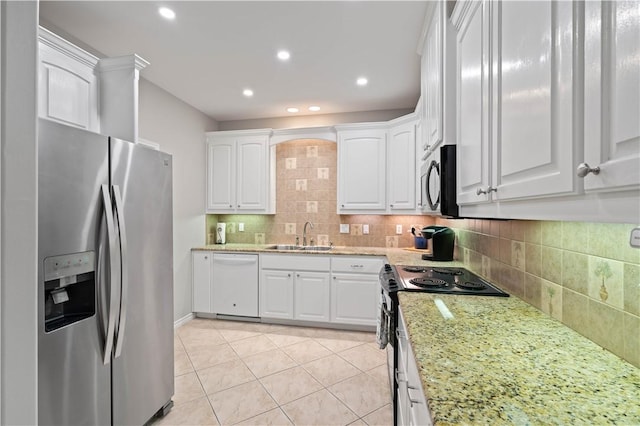 kitchen featuring backsplash, appliances with stainless steel finishes, white cabinets, a sink, and light stone countertops