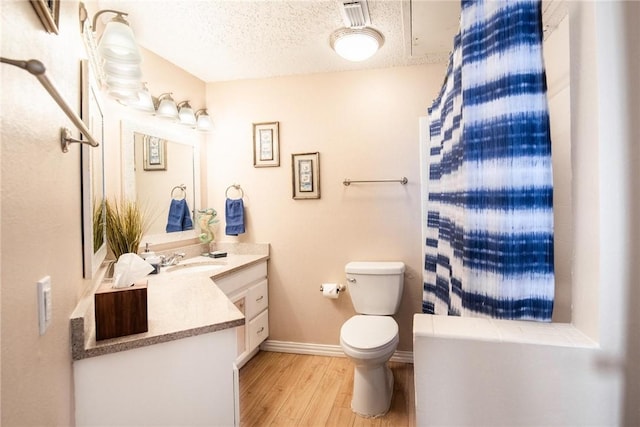 bathroom with hardwood / wood-style flooring, a textured ceiling, toilet, and vanity