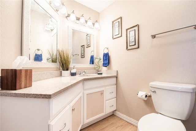 bathroom featuring wood-type flooring, toilet, and vanity