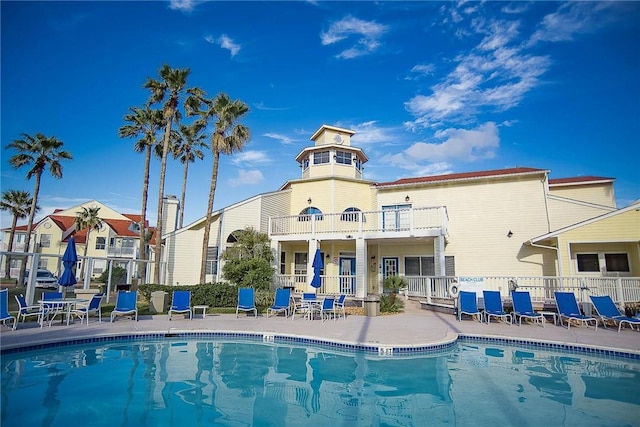 rear view of property with a community pool and a balcony