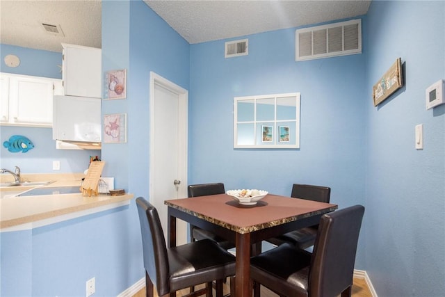 dining space with a textured ceiling, hardwood / wood-style flooring, and sink