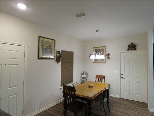 dining space featuring dark wood-type flooring and a chandelier