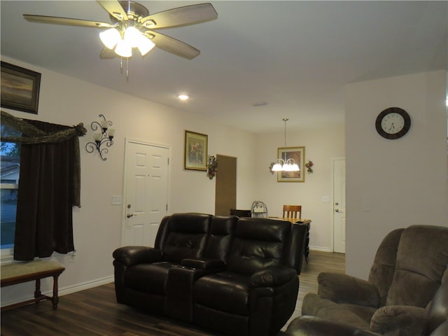 cinema room with ceiling fan with notable chandelier and dark hardwood / wood-style flooring