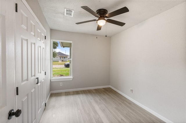 empty room featuring ceiling fan, light hardwood / wood-style flooring, and a textured ceiling