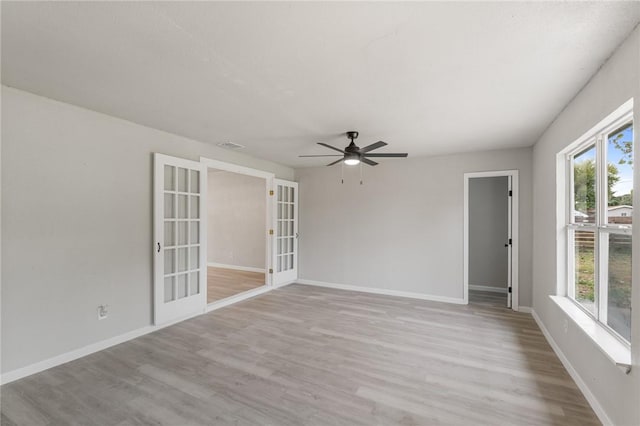 empty room with ceiling fan, light hardwood / wood-style flooring, and french doors