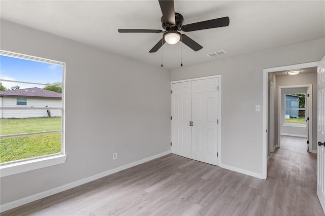 unfurnished bedroom with multiple windows, ceiling fan, and light hardwood / wood-style flooring