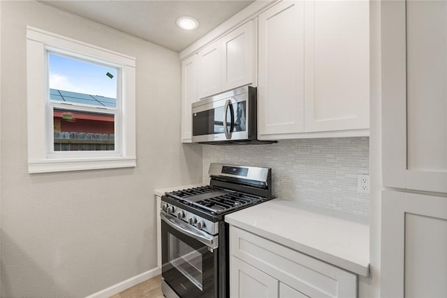 kitchen featuring stainless steel appliances, white cabinetry, and tasteful backsplash