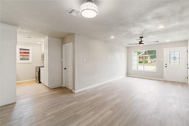 unfurnished living room with a textured ceiling, light hardwood / wood-style floors, and ceiling fan