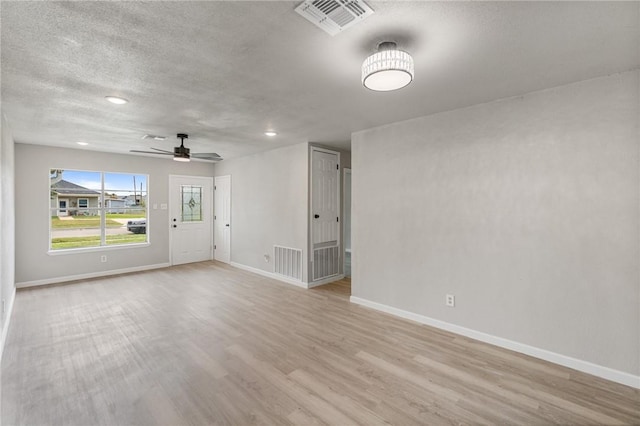 empty room with a textured ceiling, light hardwood / wood-style floors, and ceiling fan