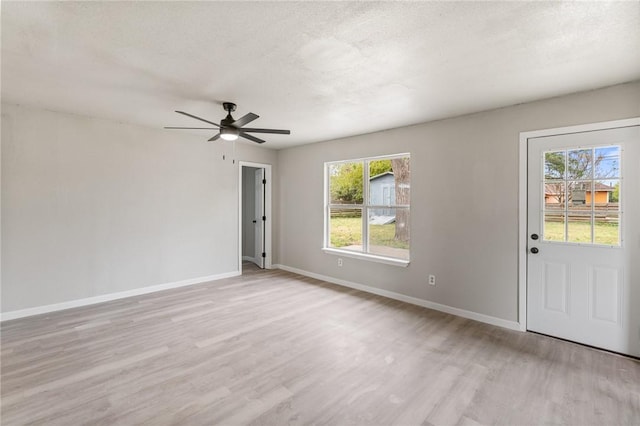 empty room with a textured ceiling, light hardwood / wood-style flooring, and ceiling fan