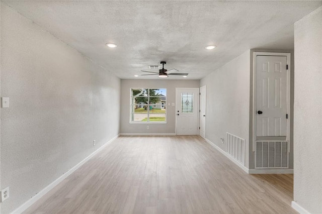 empty room featuring a textured ceiling, light hardwood / wood-style floors, and ceiling fan