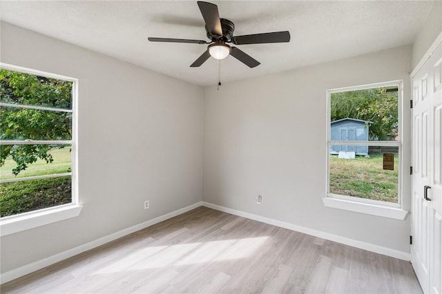 unfurnished room with plenty of natural light, ceiling fan, and light hardwood / wood-style flooring