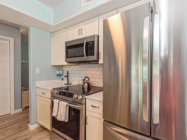 kitchen with stainless steel appliances, tasteful backsplash, and light hardwood / wood-style floors