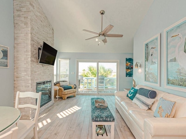 unfurnished living room featuring ceiling fan, a stone fireplace, high vaulted ceiling, and light hardwood / wood-style flooring