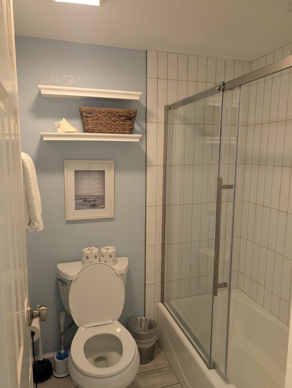 bathroom with toilet and shower / bath combination with glass door