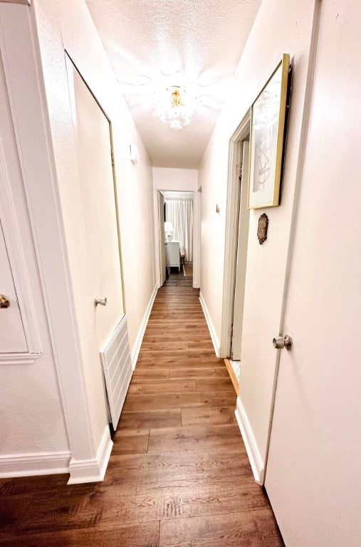 hallway with light hardwood / wood-style floors and a textured ceiling