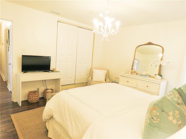 bedroom featuring an inviting chandelier, dark hardwood / wood-style flooring, and a closet