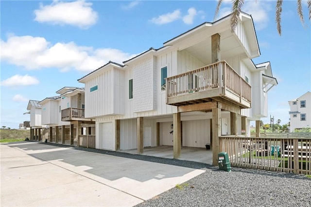 view of front of home featuring a balcony, board and batten siding, an attached garage, driveway, and a residential view