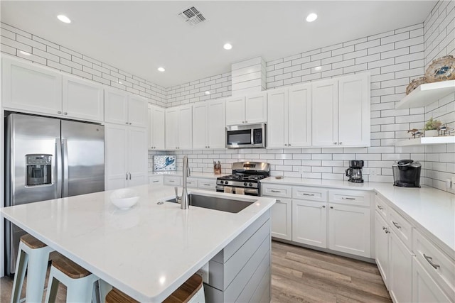 kitchen with stainless steel appliances, a sink, open shelves, a kitchen breakfast bar, and recessed lighting