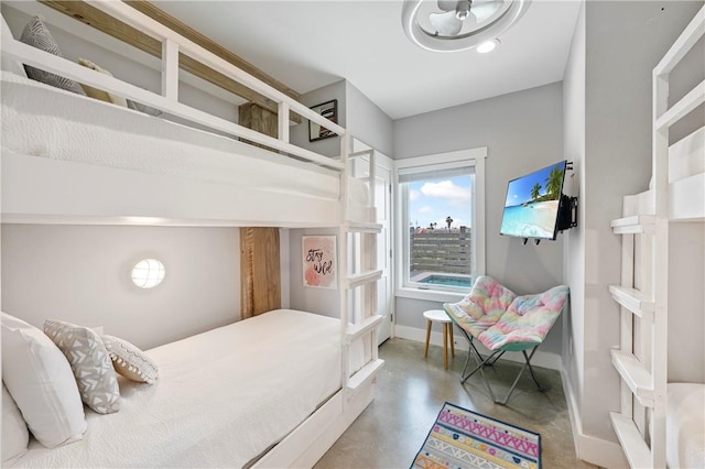 bedroom with finished concrete floors and baseboards
