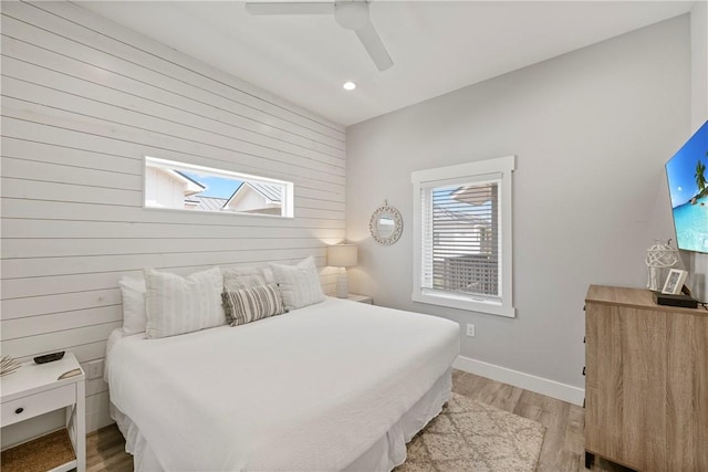 bedroom featuring light wood-style floors, wooden walls, recessed lighting, baseboards, and ceiling fan