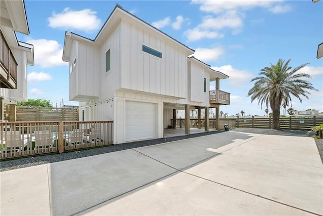 view of side of home with board and batten siding, driveway, a garage, a carport, and fence