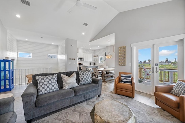 living area featuring plenty of natural light, a ceiling fan, recessed lighting, lofted ceiling, and french doors